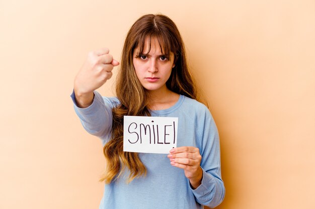 Young caucasian woman holding a Smile placard isolated