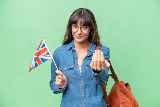 Young caucasian woman holding an United Kingdom flag over isolated background inviting to come with hand Happy that you came