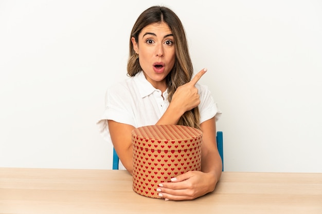 Young caucasian woman holding a valentines day box isolated pointing to the side