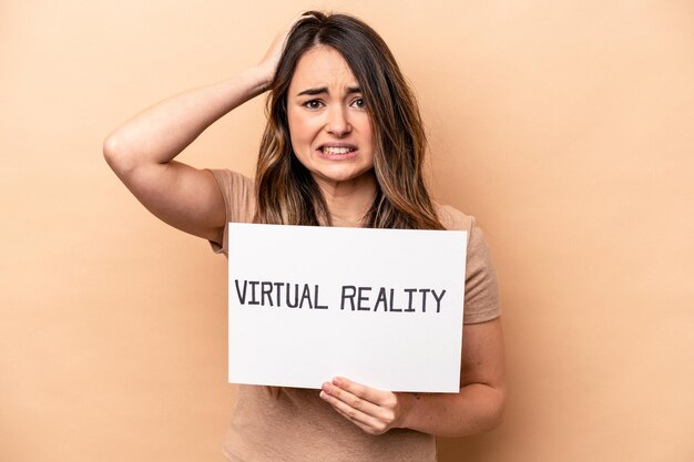 Young caucasian woman holding a virtual reality placard isolated on beige background being shocked she has remembered important meeting