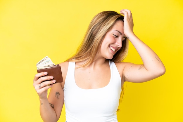 Young caucasian woman holding a wallet isolated on yellow background has realized something and intending the solution