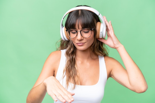 Young caucasian woman over isolated background listening music and dancing