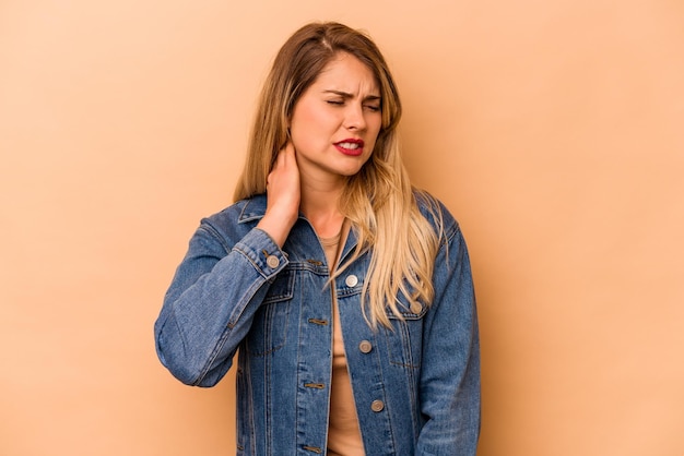 Young caucasian woman isolated on beige background having a neck pain due to stress massaging and touching it with hand