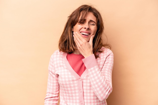 Young caucasian woman isolated on beige background having a strong teeth pain molar ache