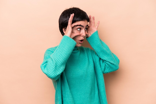 Young caucasian woman isolated on beige background keeping eyes opened to find a success opportunity.