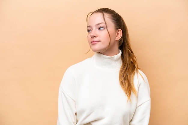 Photo young caucasian woman isolated on beige background looking to the side