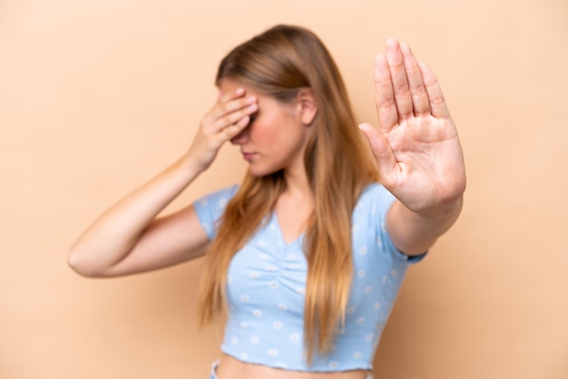 Young caucasian woman isolated on beige background making stop gesture and covering face