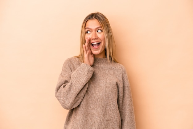 Young caucasian woman isolated on beige background shouting excited to front.