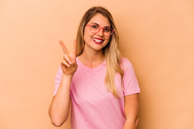 Young caucasian woman isolated on beige background showing number two with fingers