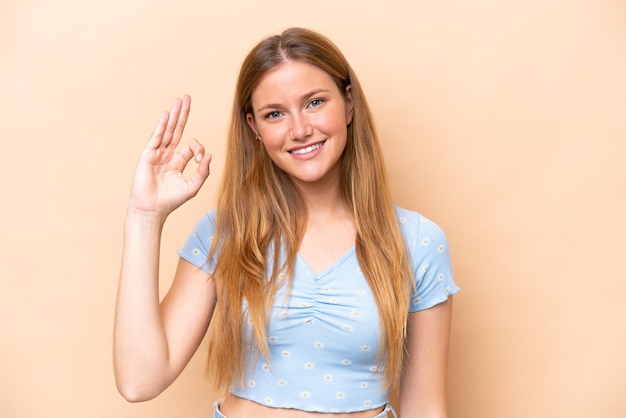 Young caucasian woman isolated on beige background showing ok sign with fingers