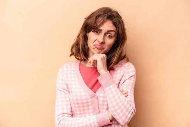 Young caucasian woman isolated on beige background thinking and looking up being reflective contemplating having a fantasy