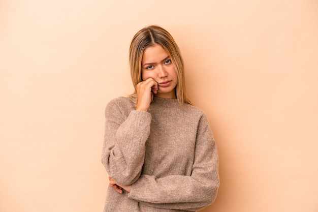 Young caucasian woman isolated on beige background tired of a repetitive task.