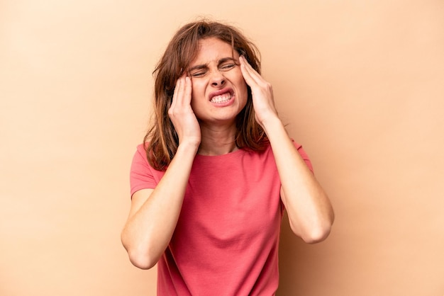 Young caucasian woman isolated on beige background touching temples and having headache