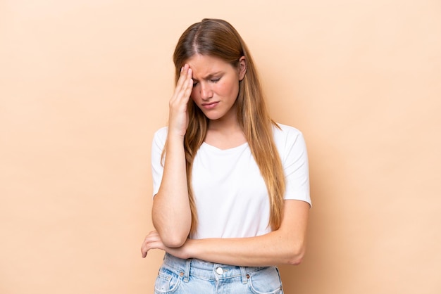 Young caucasian woman isolated on beige background with headache