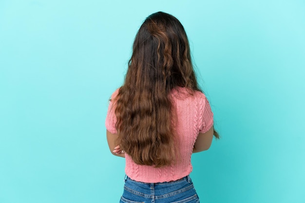 Young caucasian woman isolated on blue background in back position