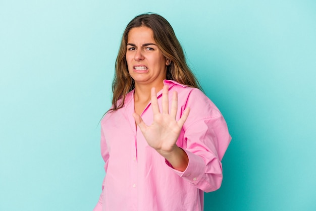 Young caucasian woman isolated on blue background  being shocked due to an imminent danger