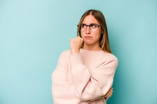 Young caucasian woman isolated on blue background confused feels doubtful and unsure