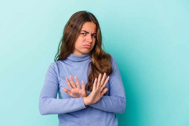 Young caucasian woman isolated on blue background  doing a denial gesture