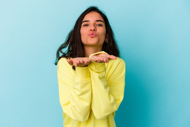 Young caucasian woman isolated on blue background folding lips and holding palms to send air kiss.