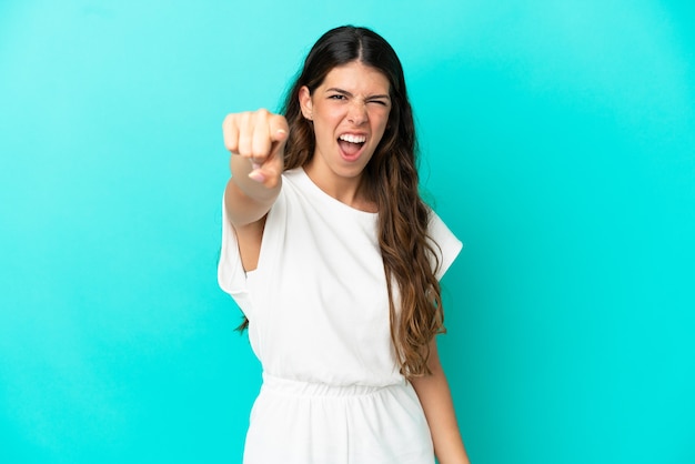 Young caucasian woman isolated on blue background frustrated and pointing to the front