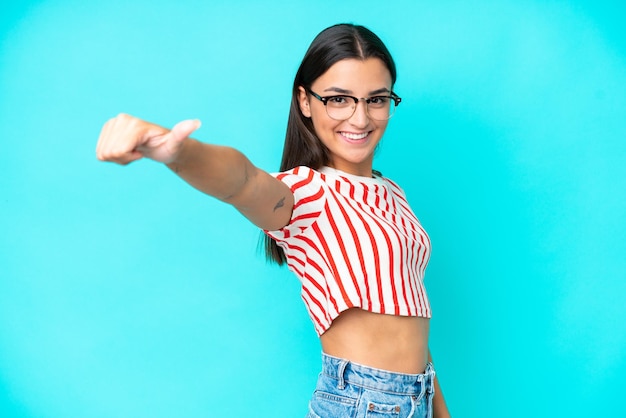 Young caucasian woman isolated on blue background giving a thumbs up gesture