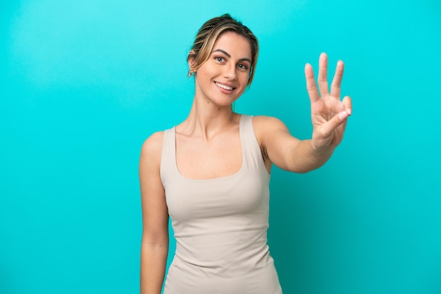 Young caucasian woman isolated on blue background happy and counting three with fingers