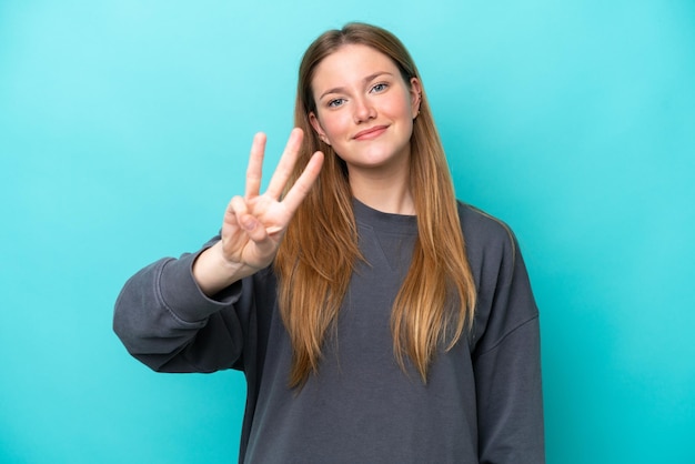 Young caucasian woman isolated on blue background happy and counting three with fingers