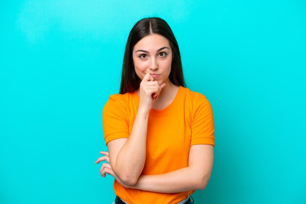 Young caucasian woman isolated on blue background having doubts and thinking