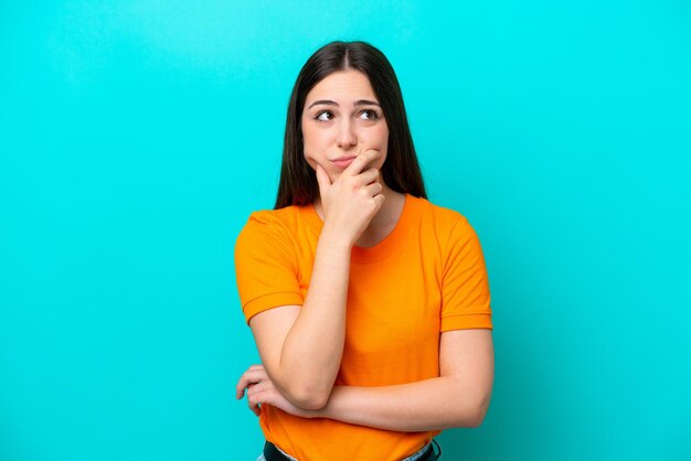 Young caucasian woman isolated on blue background having doubts