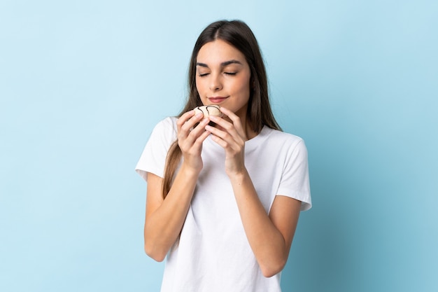 Young caucasian woman isolated on blue background holding a donut