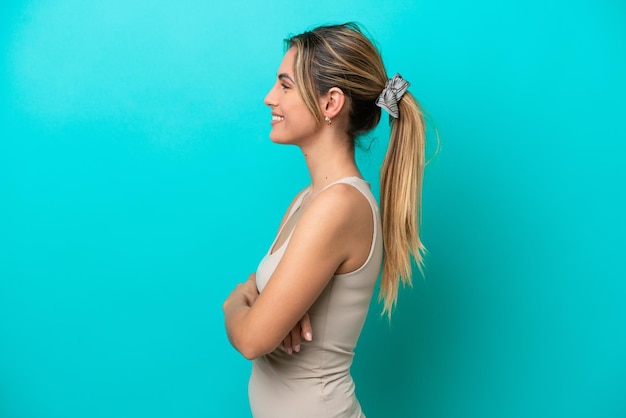 Young caucasian woman isolated on blue background in lateral position