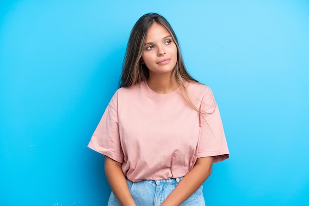 Photo young caucasian woman isolated on blue background looking to the side