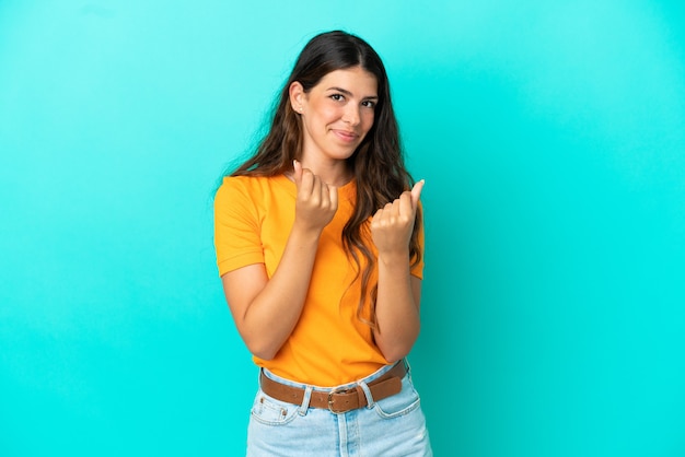 Young caucasian woman isolated on blue background making money gesture but is ruined