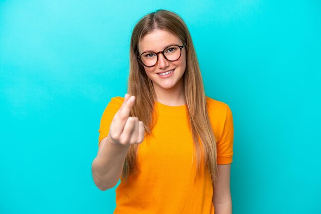 Young caucasian woman isolated on blue background making money gesture