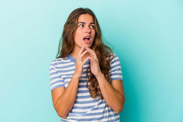 Young caucasian woman isolated on blue background  making up plan in mind, setting up an idea.