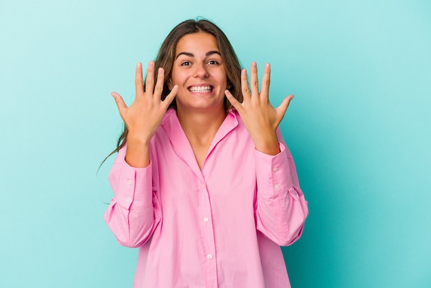 Young caucasian woman isolated on blue background  showing number ten with hands.