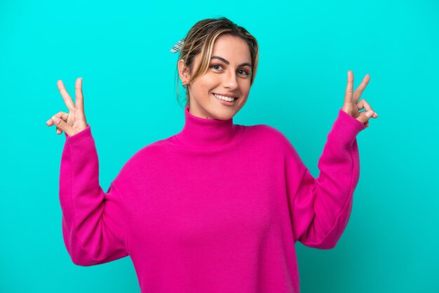 Young caucasian woman isolated on blue background showing victory sign with both hands