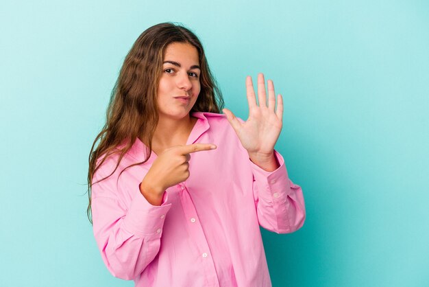 Young caucasian woman isolated on blue background  smiling cheerful showing number five with fingers.