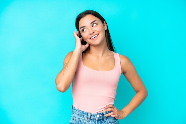 Young caucasian woman isolated on blue background thinking an idea