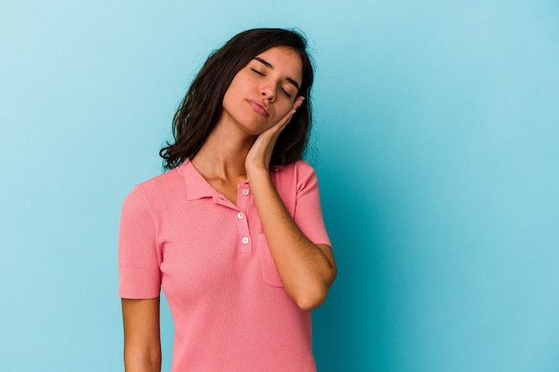 Young caucasian woman isolated on blue background who is bored, fatigued and need a relax day.