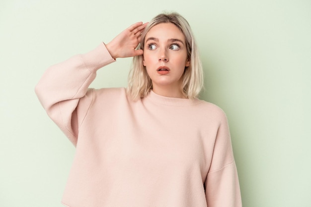 Young caucasian woman isolated on green background being shocked, she has remembered important meeting.