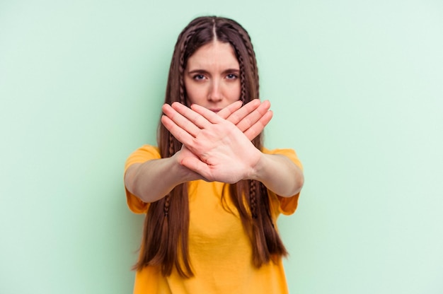 Young caucasian woman isolated on green background doing a denial gesture