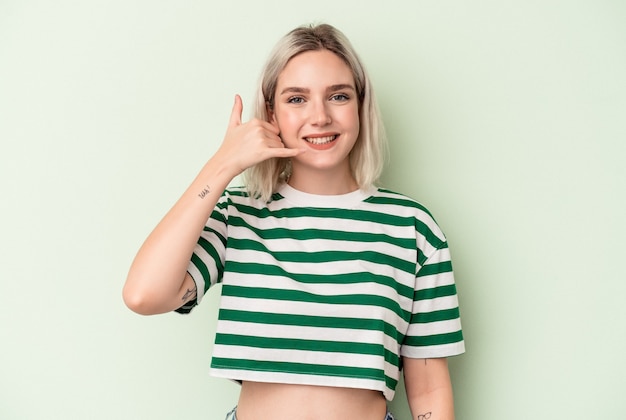 Young caucasian woman isolated on green background showing a mobile phone call gesture with fingers.