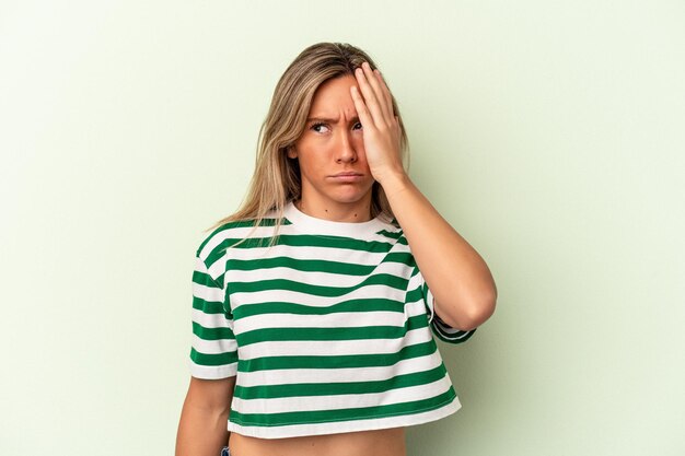 Young caucasian woman isolated on green background tired and very sleepy keeping hand on head.