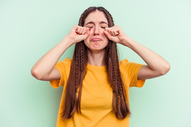 Photo young caucasian woman isolated on green background whining and crying disconsolately.