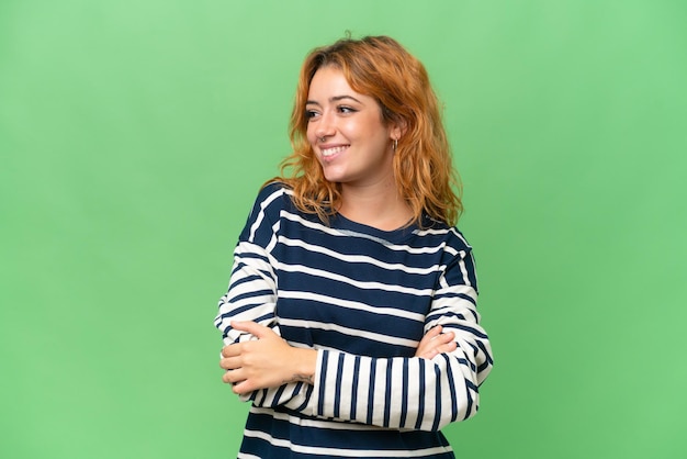 Young caucasian woman isolated on green screen chroma key background looking to the side and smiling