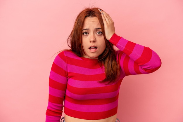 Young caucasian woman isolated on pink background being shocked, she has remembered important meeting.