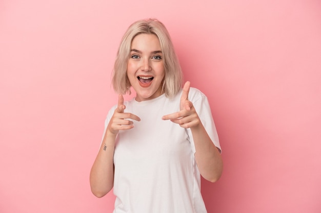 Young caucasian woman isolated on pink background cheerful smiles pointing to front.