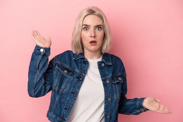 Young caucasian woman isolated on pink background confused and doubtful shrugging shoulders to hold a copy space