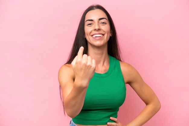 Young caucasian woman isolated on pink background doing coming gesture